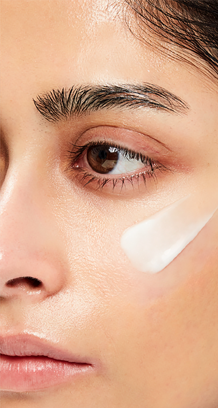 Close-up of woman applying Aestura lotion under her eye